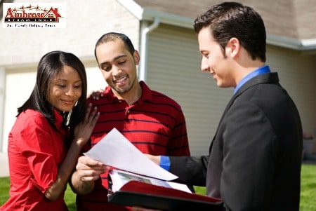 male real estate agent with couple in front of home