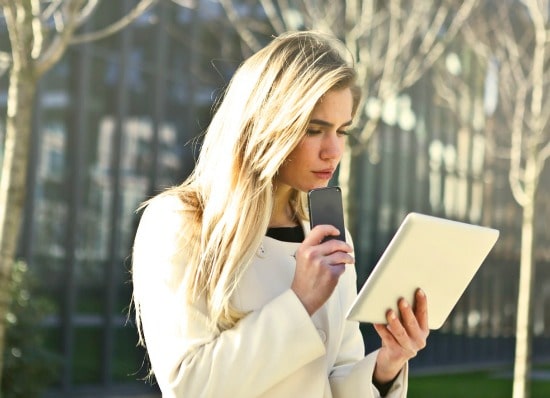 Woman looking at tablet and holding phone