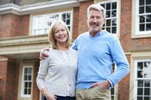 55+ couple in front of house