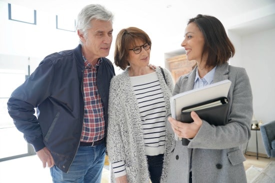 55+ couple looking at patio home with real estate agent