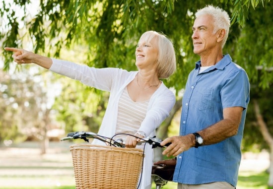 55+ woman and man with bike, woman is pointing to something out of shot and smiling