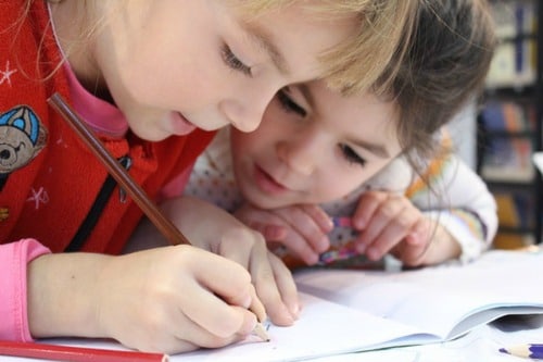 two elementary age girls drawing with a pencil