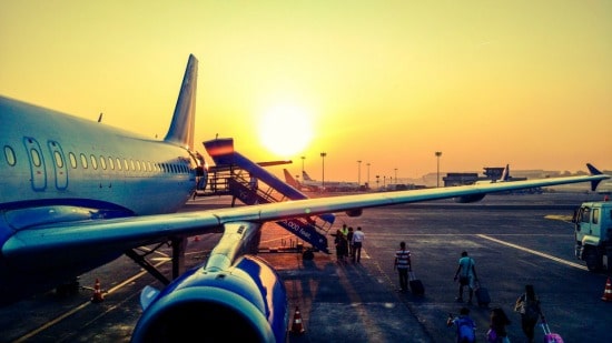 people boarding a plane at sunset on the runway