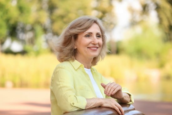 woman in yellow shirt standing at a rail and smiling