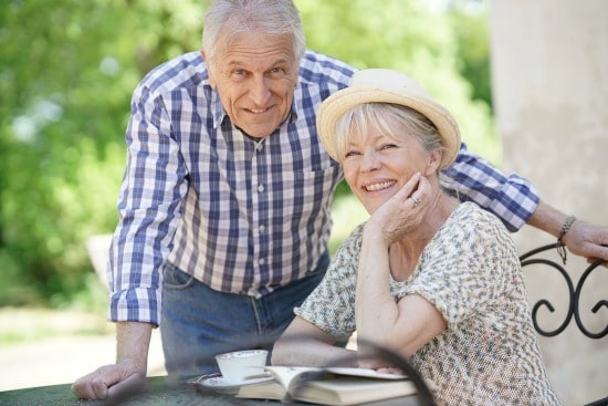 senior woman smiling at camera while senior man stands nearby