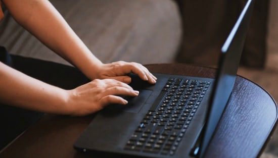womans hands using laptop keyboard