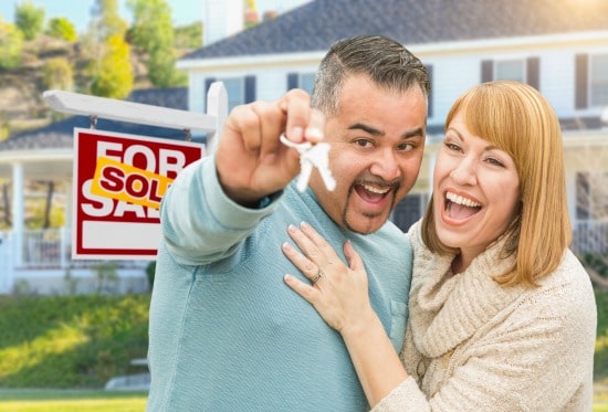 man and woman embracing and smiling with man holding house keys