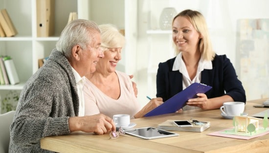 55+ couple with real estate agent looking over paperwork